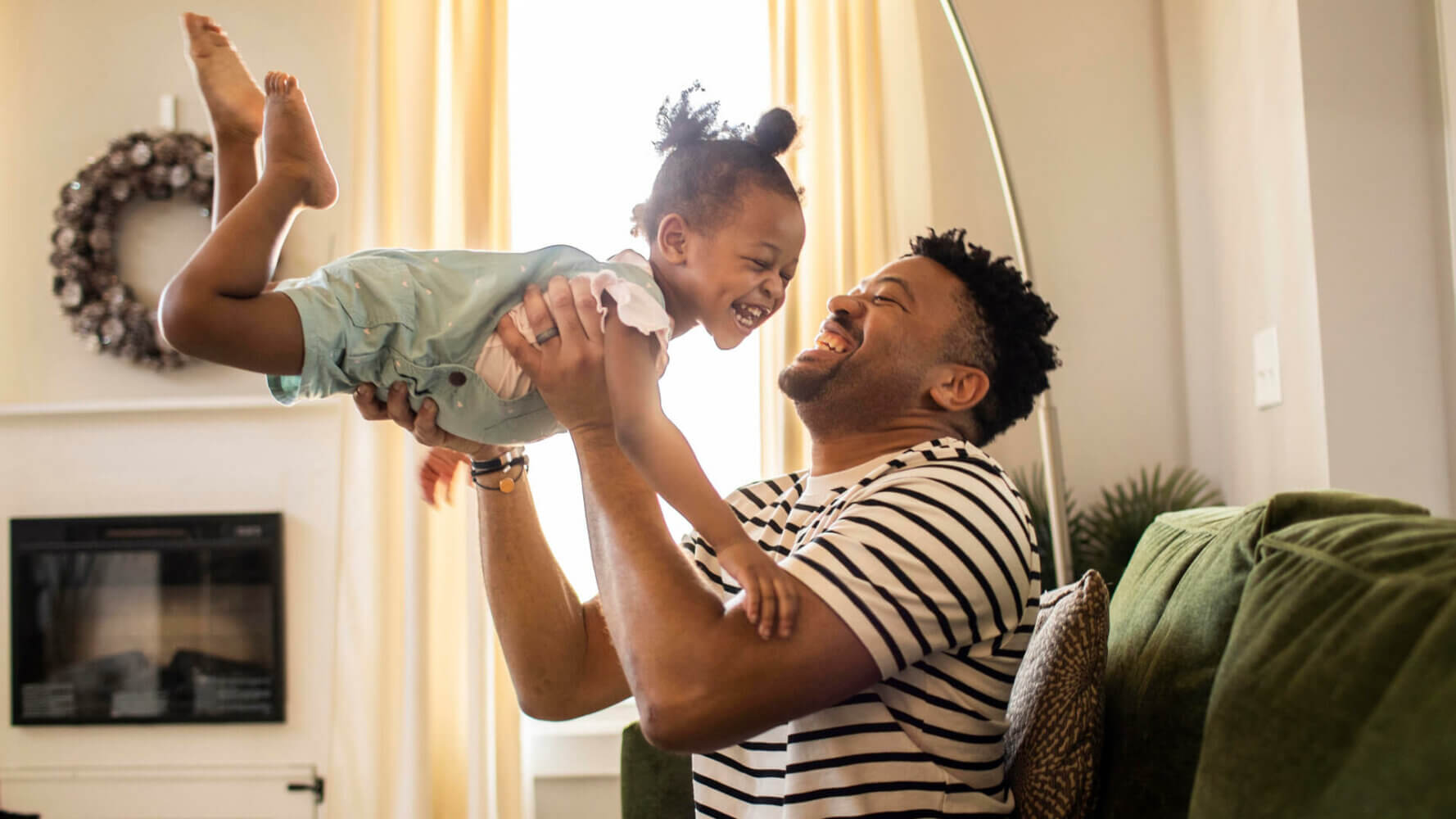 Father lifting toddler daughter in the air, values