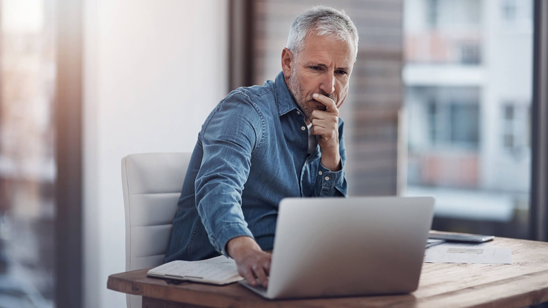 Cropped shot of a thoughtful mature businessman looking at his business and analyzing the effect of inflation