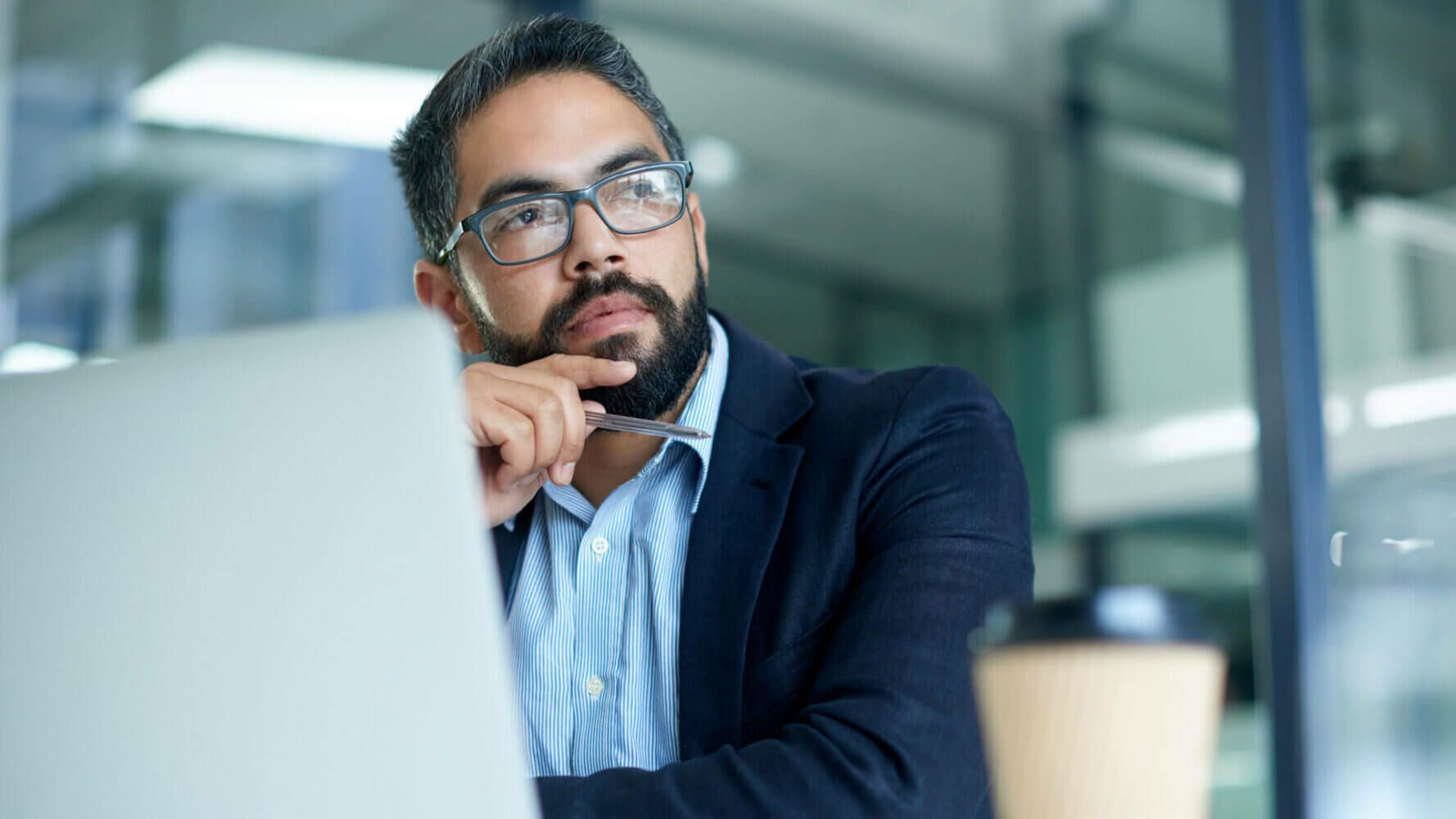 A man looks wistfully past his computer, thinking about how if consumers buy brands, do I have a brand?