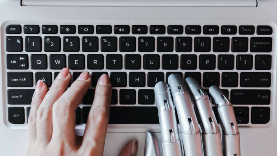 A human hand and an AI hand type on the same keyboard.