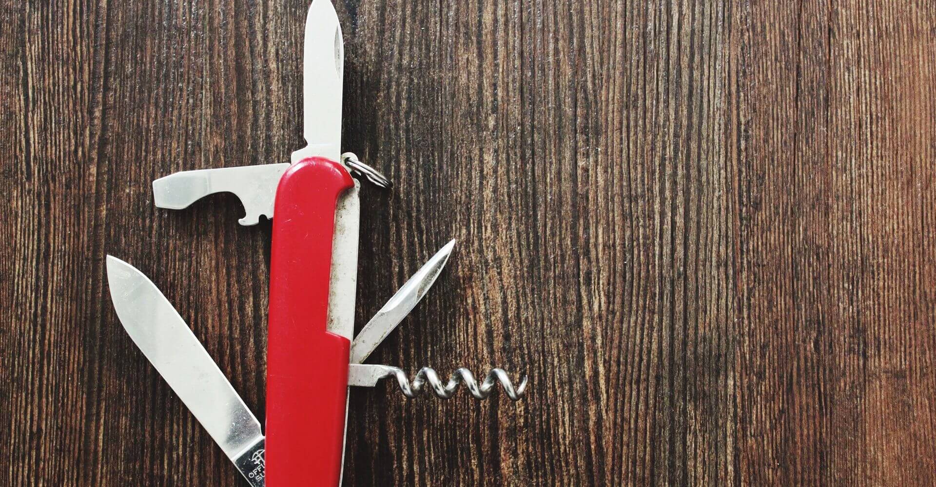 A swiss army knife lies open on a wood table, dividend paying stocks are the investors swiss army knife