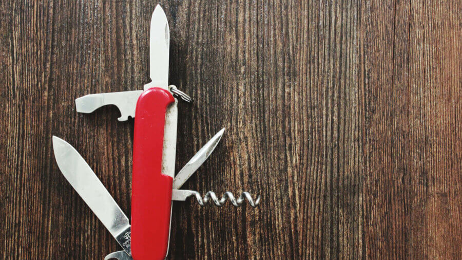 A swiss army knife lies open on a wood table, dividend paying stocks are the investors swiss army knife