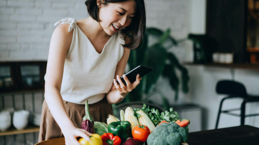 A woman picks out a bright yellow bell pepper for dinner.