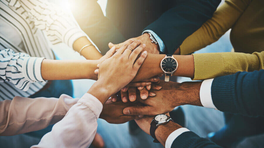 A team piles their hands to celebrate a big success.