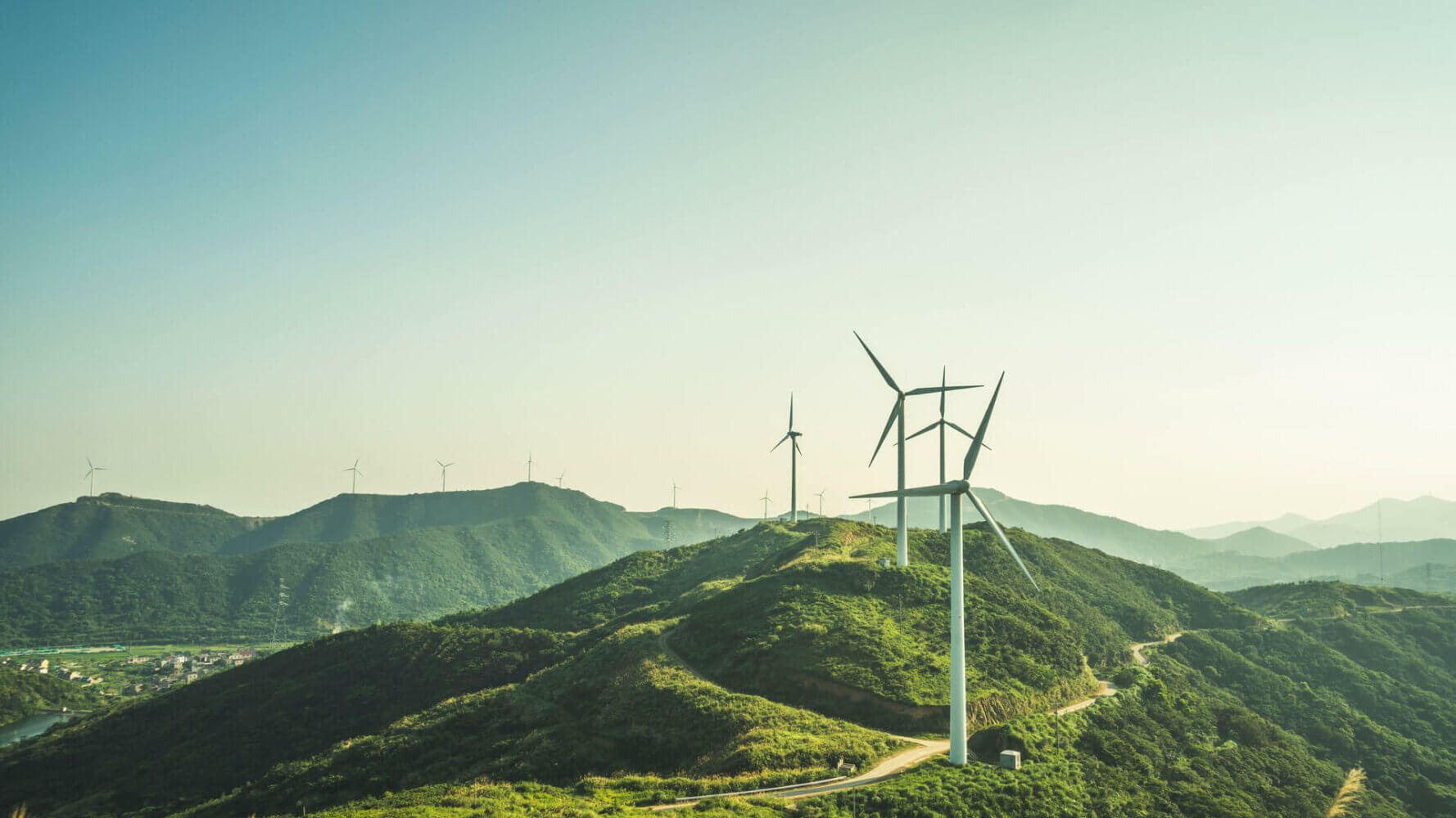 ESG Investing: windmills stand in the distance along a hill