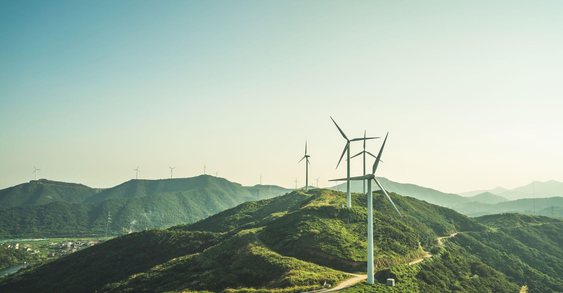 ESG Investing: windmills stand in the distance along a hill