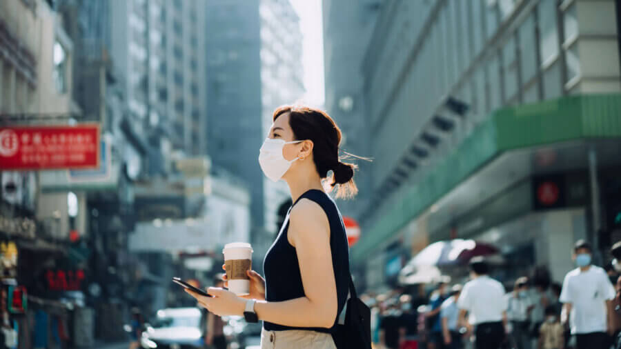 A woman in Asia stands in a busy road wearing a mask to protect against COVID-19, international growth opportunities