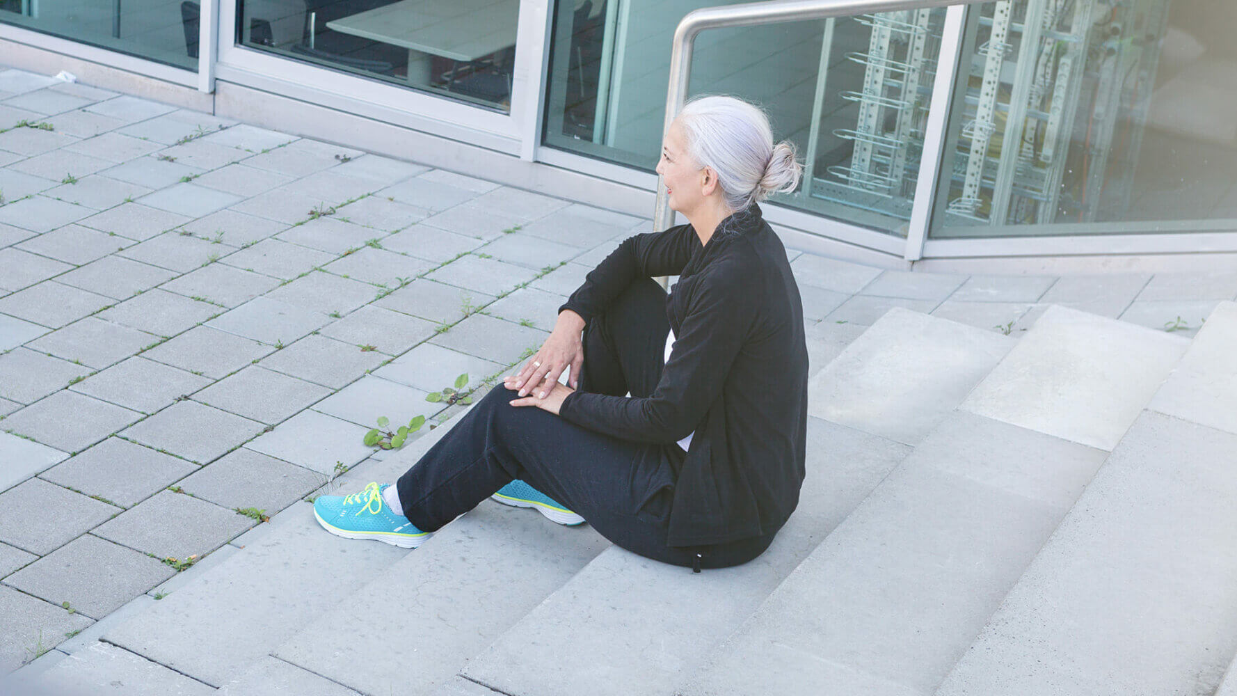 Side view of mature woman sat on urban steps in tracksuit