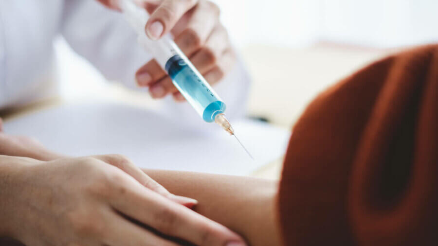 Close up doctor hand holding syringe injection needle for patient arm