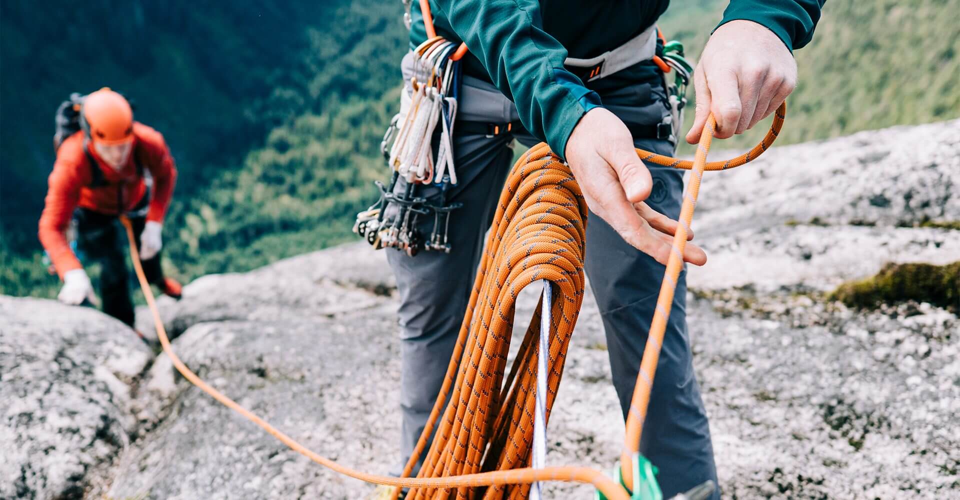 Managing risk is shown as two climbers use safety rope to pull themselves up a cliff face.