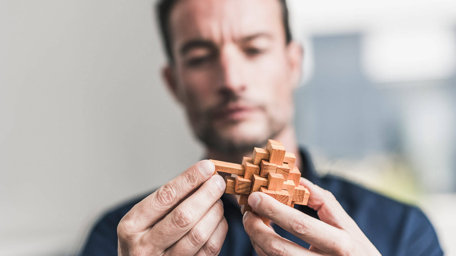 Man looks to figure out wooden puzzle piece.