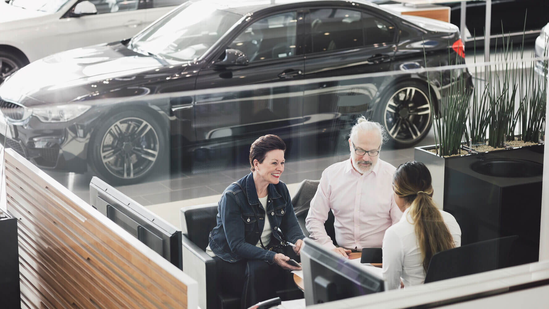 Couple discusses buying a new car with a sales rep.