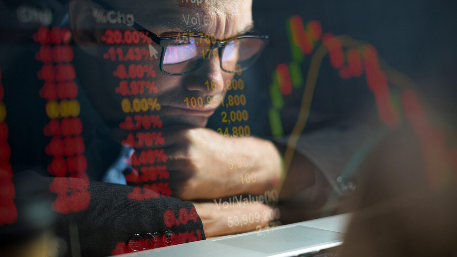 Man stares into a reflection showing stock market stats.