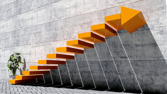 Bright orange stairs lead up against a stark industrial grey wall