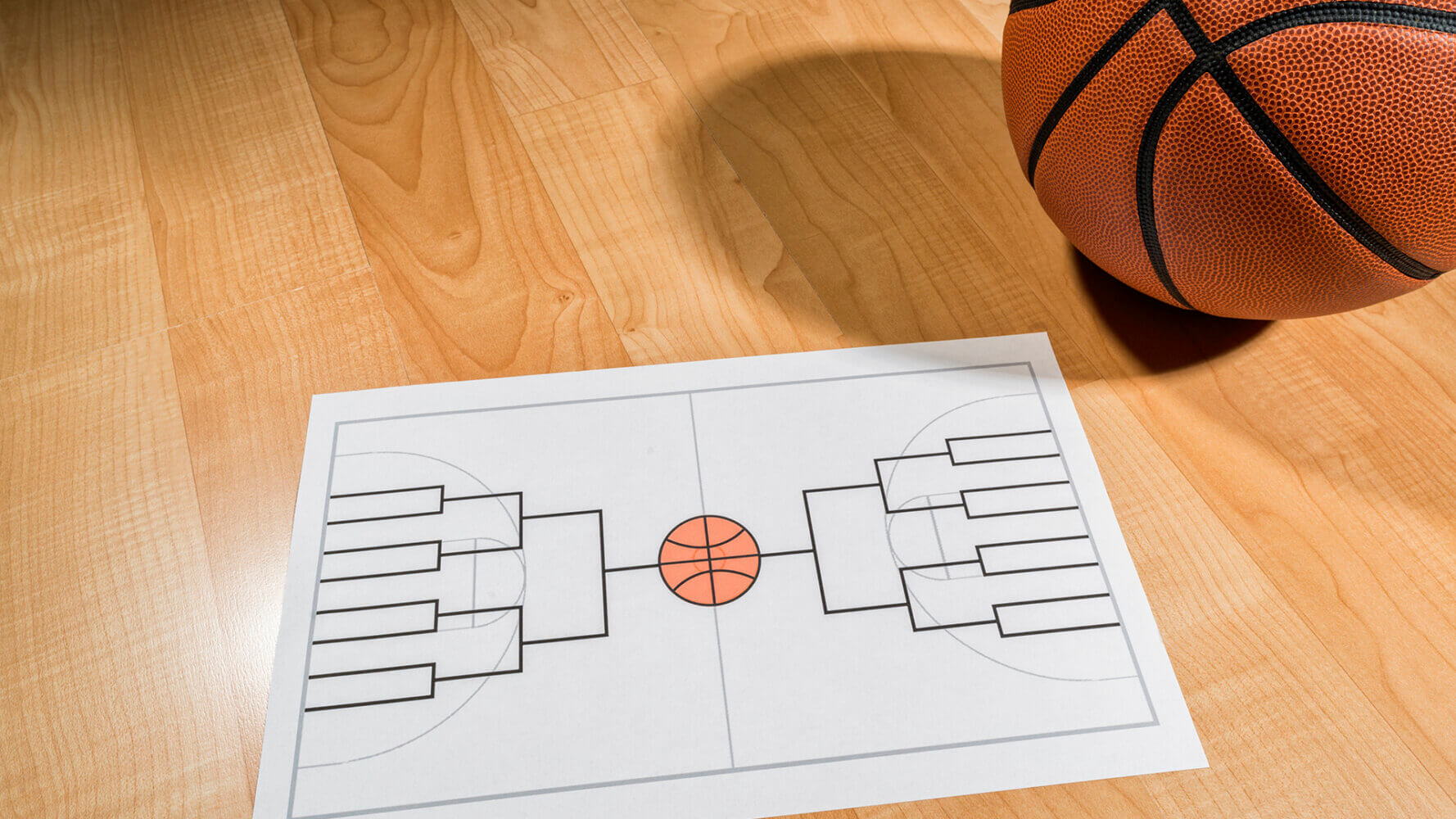 Basketball and a March Madness Bracket diagram laying on the court.