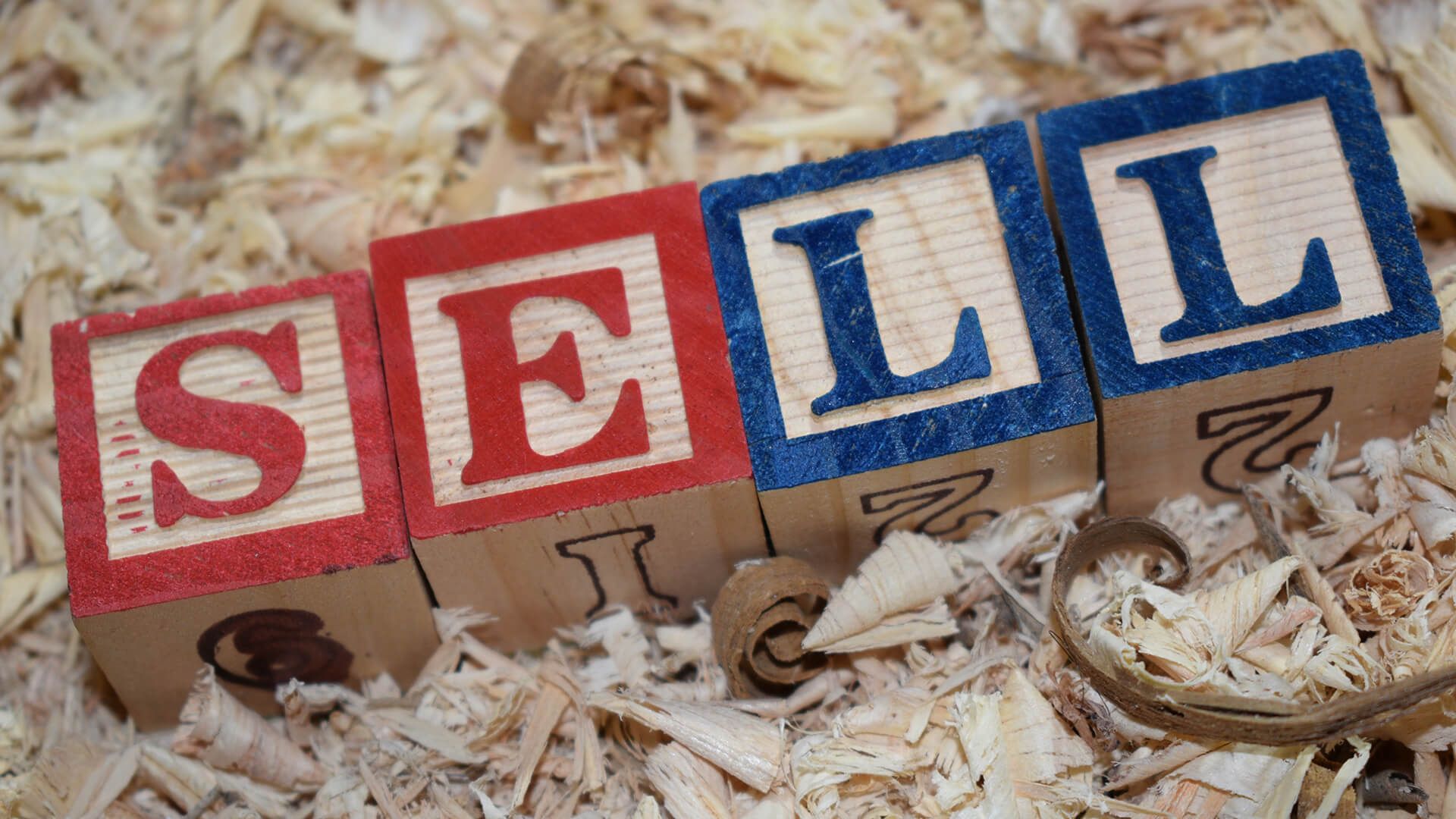 Wooden block with word SELL placed in the wooden saw dust