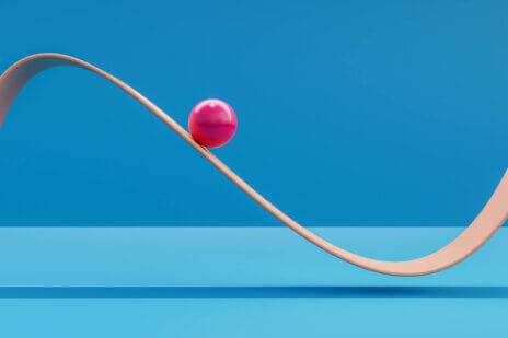 Computer generated image of pink sphere rolling down a plane like a roller coaster.