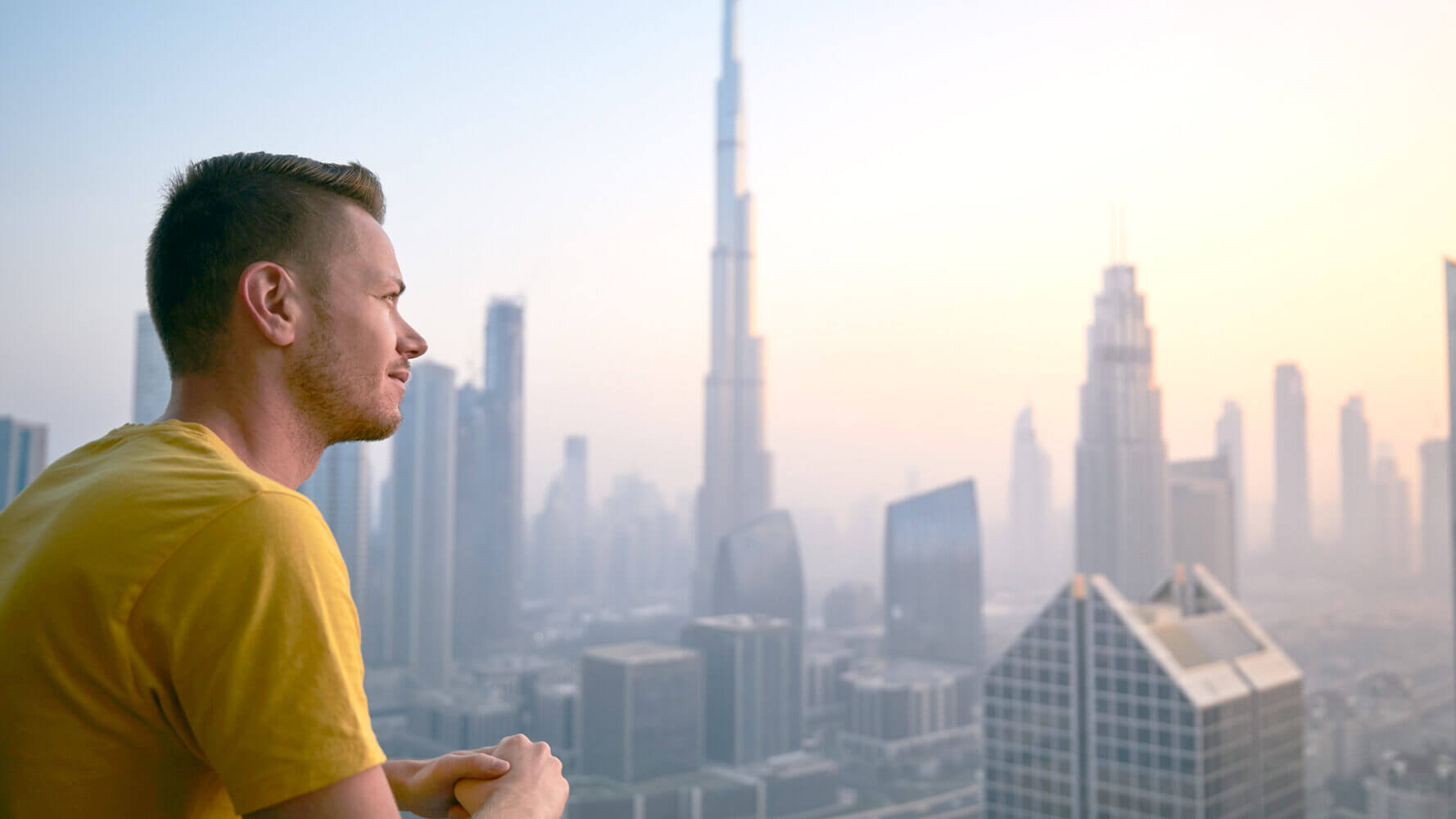 Man looking out across the dawn of a city's horizon.