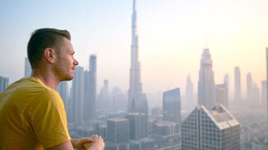 Man looking out across the dawn of a city's horizon.