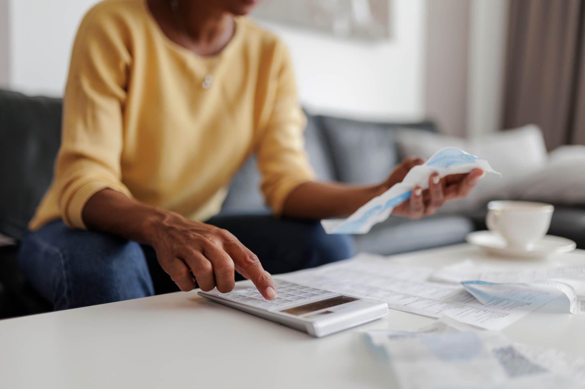 Close up of a mid adult woman checking her energy bills at home, sitting in her living room. She has a worried expression