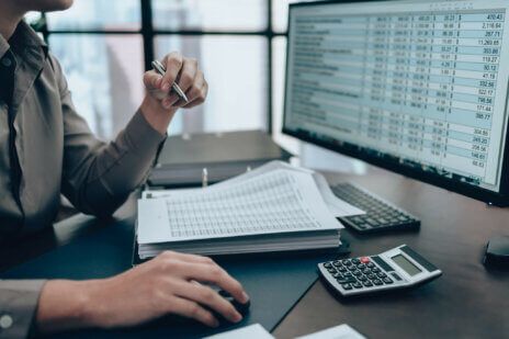 Woman sits at desktop in her office analyzing financial records