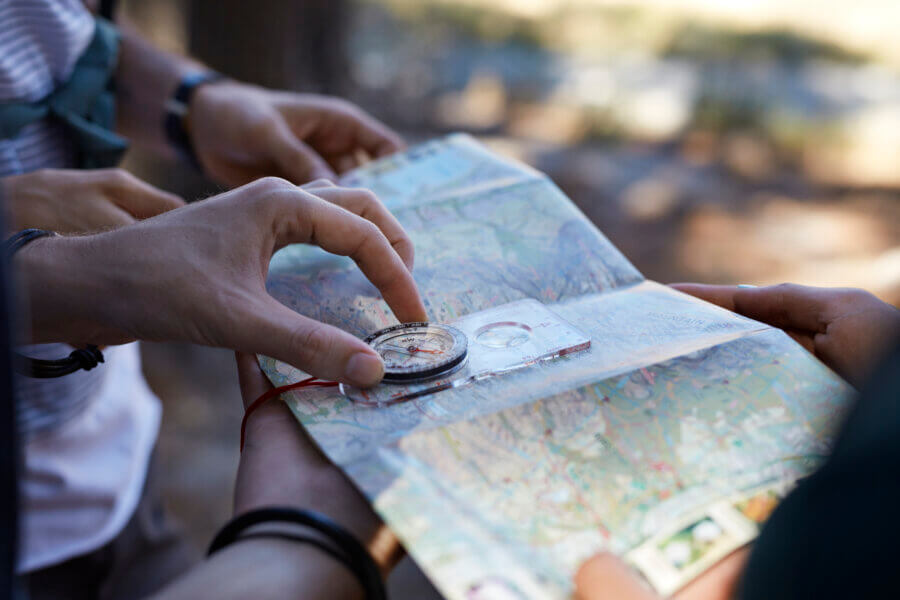 A few people using a map and a compass to pinpoint their current location and future destination.